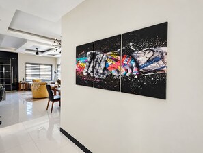 Ein modernes Interieur mit einer mehrteiligen Wandkunst, einem gelben Sofa und einem Essbereich.