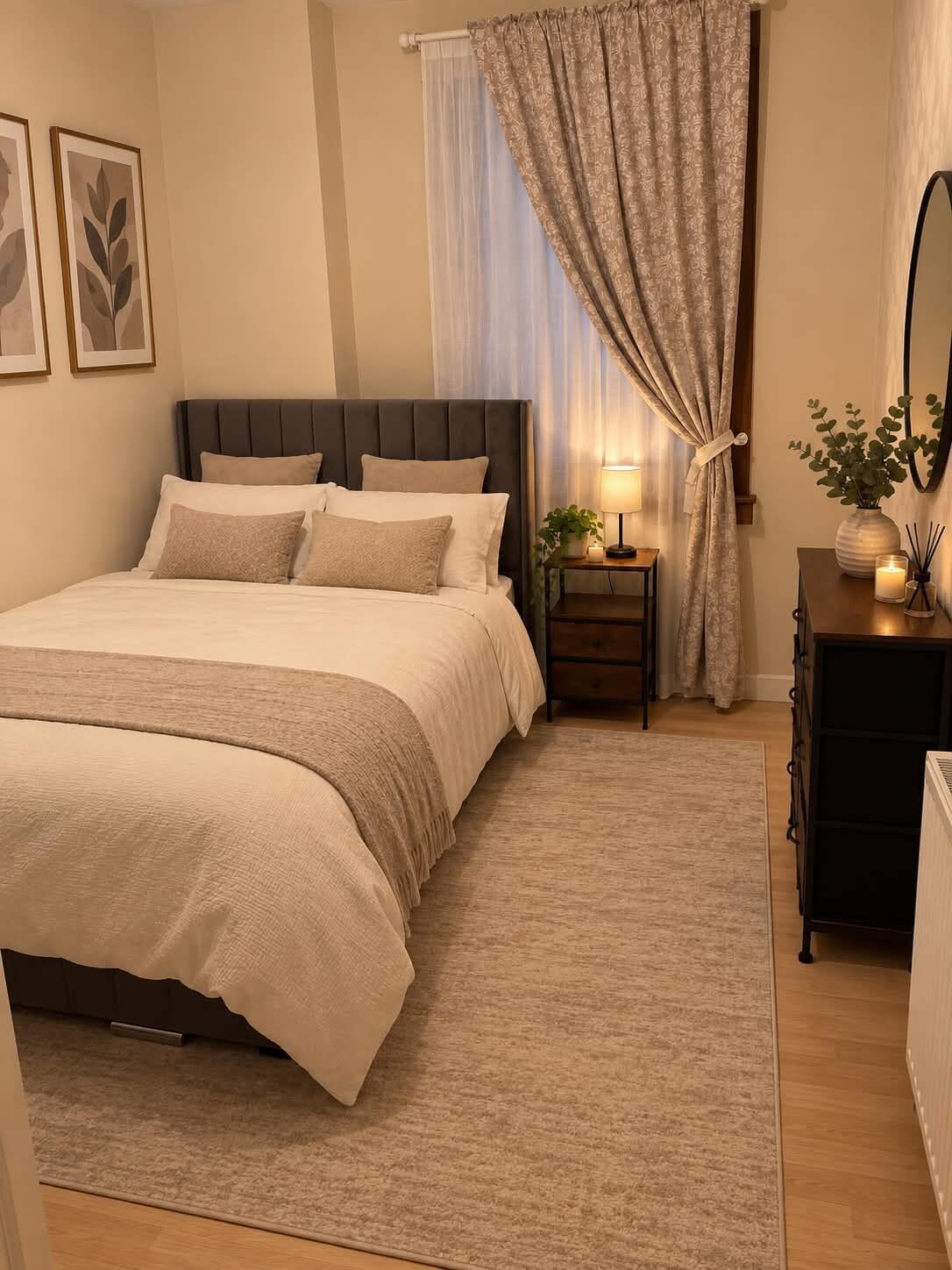 Een keurig opgemaakt slaapkamer met een bed, nachtkastje, lamp en een dressoir.