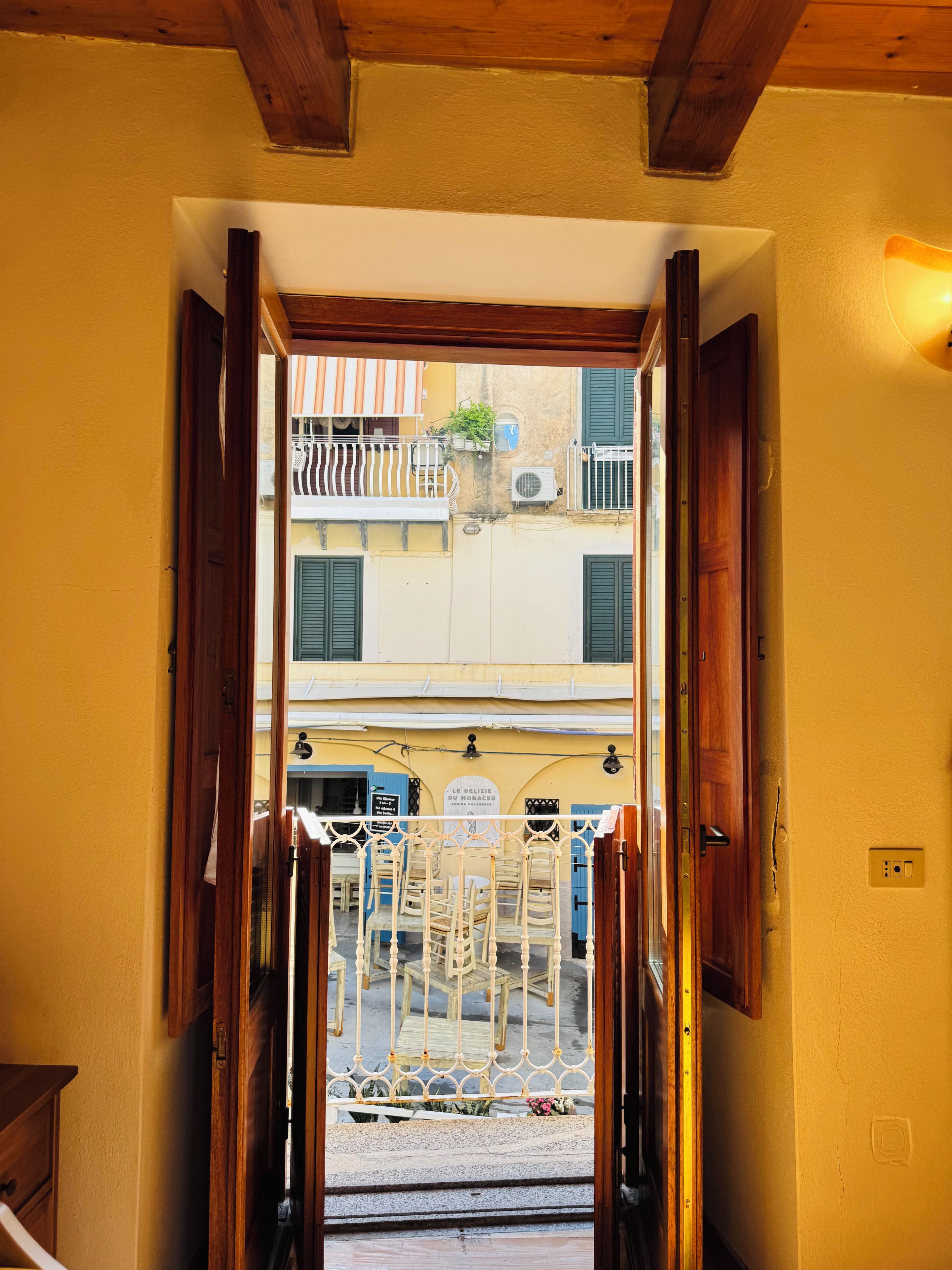Un ingresso che dà su un cortile con mobili da esterno e una segnaletica che indica un ristorante.