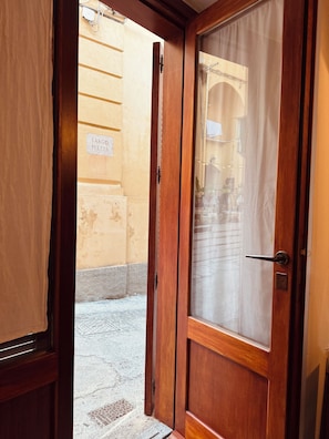 An open wooden door leading to a street with a sign reading 'Largo Frezza'. - Tropea Eye (Tropea)