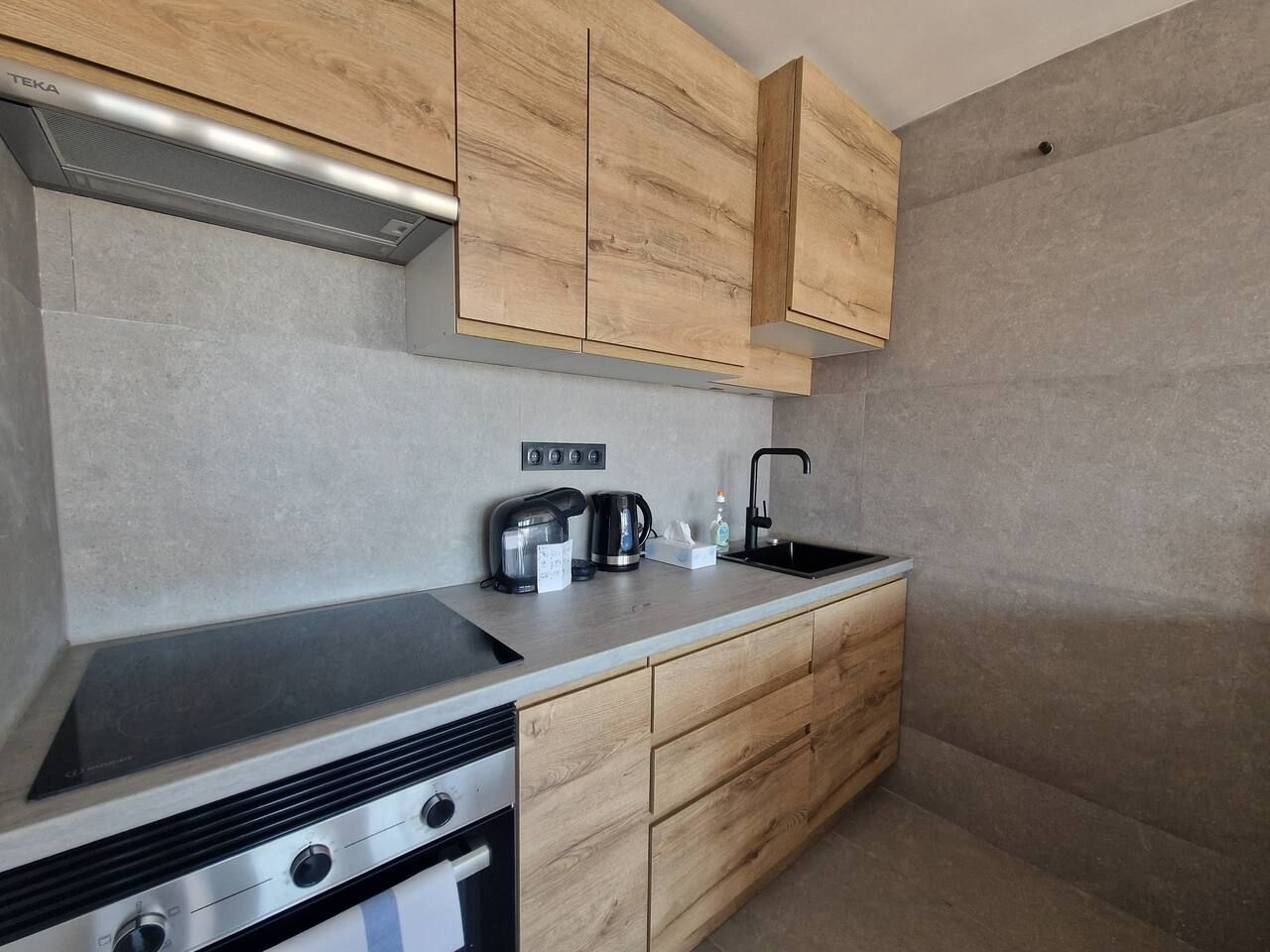 A modern kitchen with wooden cabinets, a stainless steel sink, and a built-in oven.