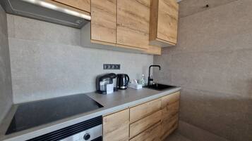 A modern kitchen with wooden cabinets, a stainless steel sink, and a built-in oven.