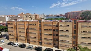 Un edificio residencial de varios pisos con un estacionamiento en frente.