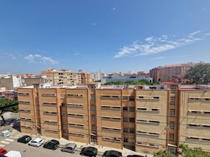 Edifício residencial de vários andares com área de estacionamento na frente.