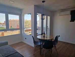 Uma sala de estar moderna com área de jantar, janelas amplas e um aparelho de ar condicionado.