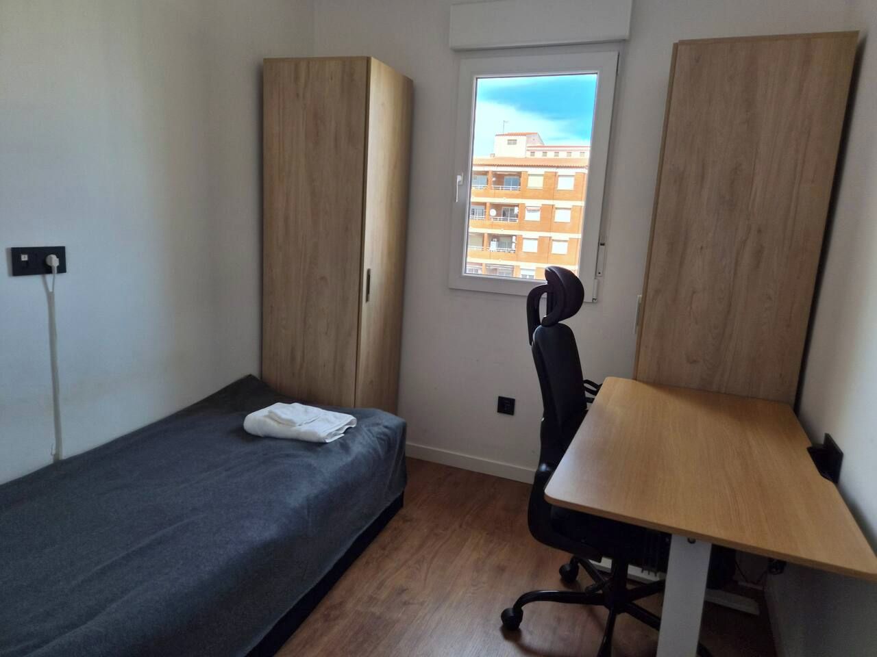 Un alojamiento pequeño y con una sola habitación, con cama, escritorio y silla.