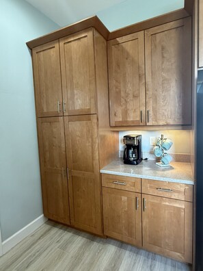 A kitchen with wooden cabinets, a coffee maker, and a countertop. - Pool + Dock + 3 Bedrooms + No Bridge Gulf access (Englewood)