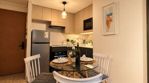 A compact kitchen with modern appliances, a dining table with chairs, and a small island.