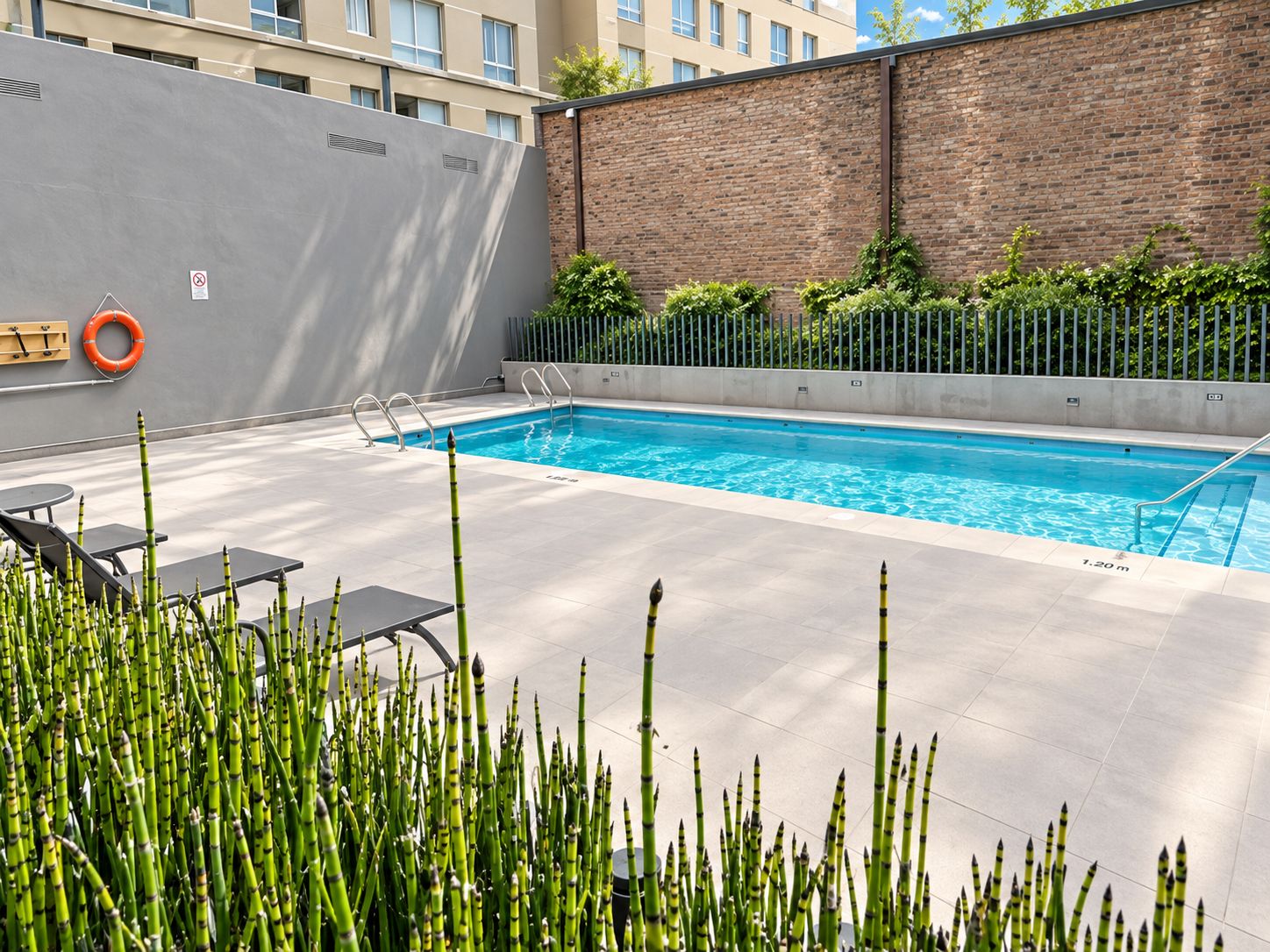Une piscine équipée d’une bouée de sauvetage, d’un banc et d’une rambarde.