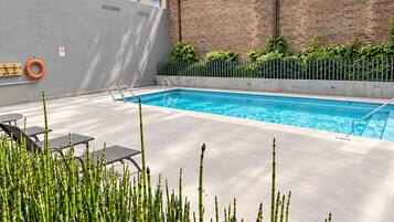 Une piscine équipée d’une bouée de sauvetage, d’un banc et d’une rambarde.