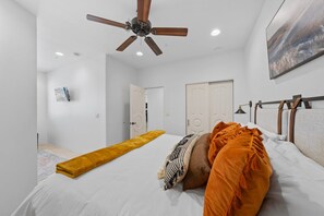 A bedroom with a bed, a ceiling fan, a painting, and a door. - Fountain Hills Hideaway: Pool, Views, Game Room (Fountain Hills)