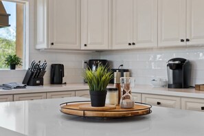 A kitchen with white cabinets, a coffee maker, a kettle, and a plant on a countertop. - Fountain Hills Hideaway: Pool, Views, Game Room (Fountain Hills)