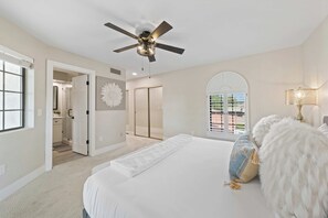 A bedroom with a large bed, a ceiling fan, a walk-in closet, and a view through a window. - The Scottsdale Compound: Pool, Putt, Play, Repeat (Scottsdale)
