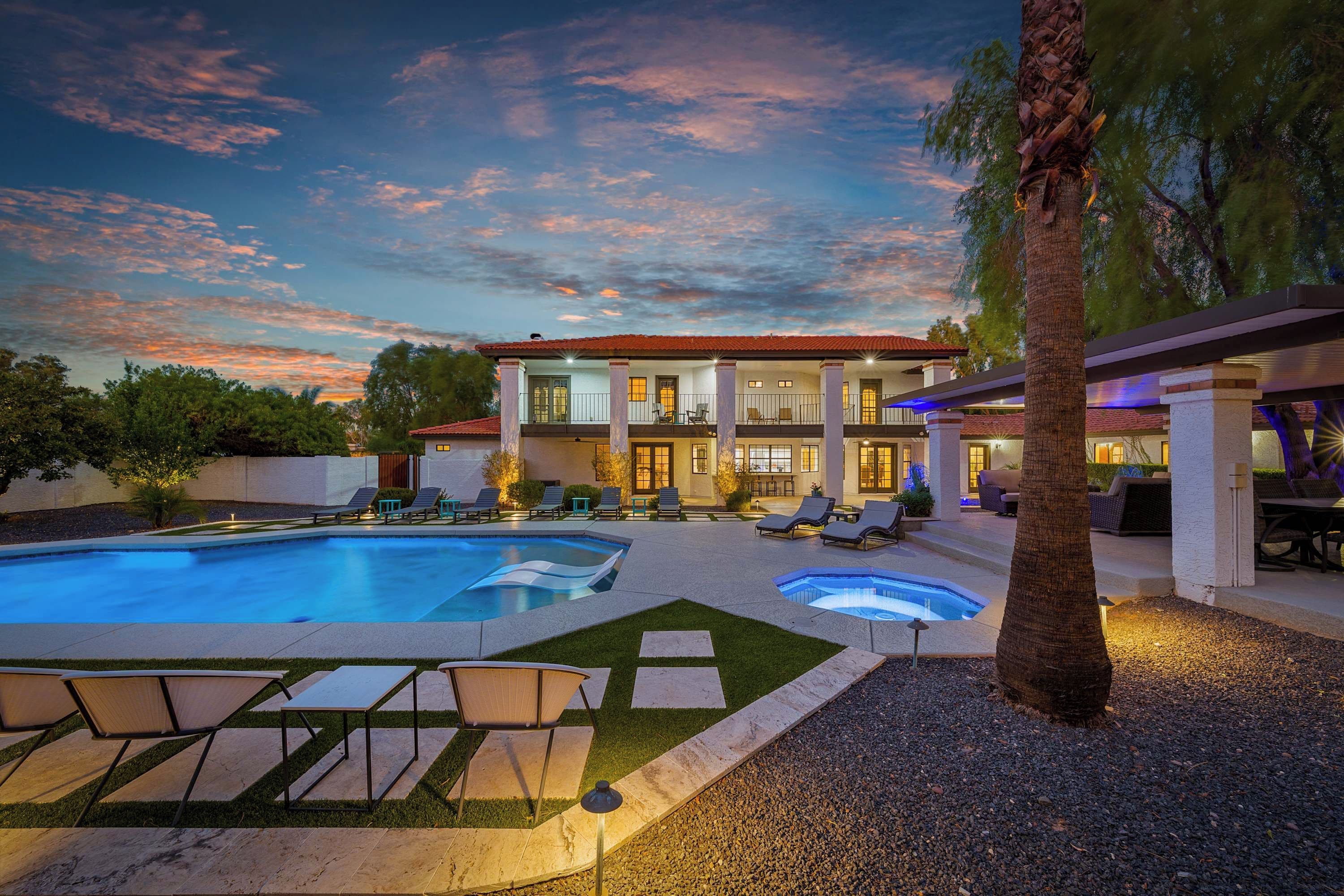 A two-story house with a swimming pool, outdoor seating, and a well-maintained garden.