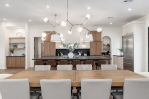 Eine moderne Küche mit einer zentralen Kochinsel, Holzschränken und einem Edelstahl-Kühlschrank.