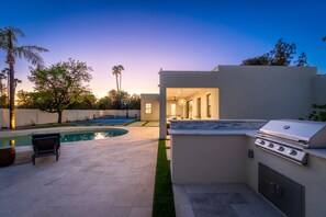 Ein Garten mit Swimmingpool, Grill und Basketballkorb.