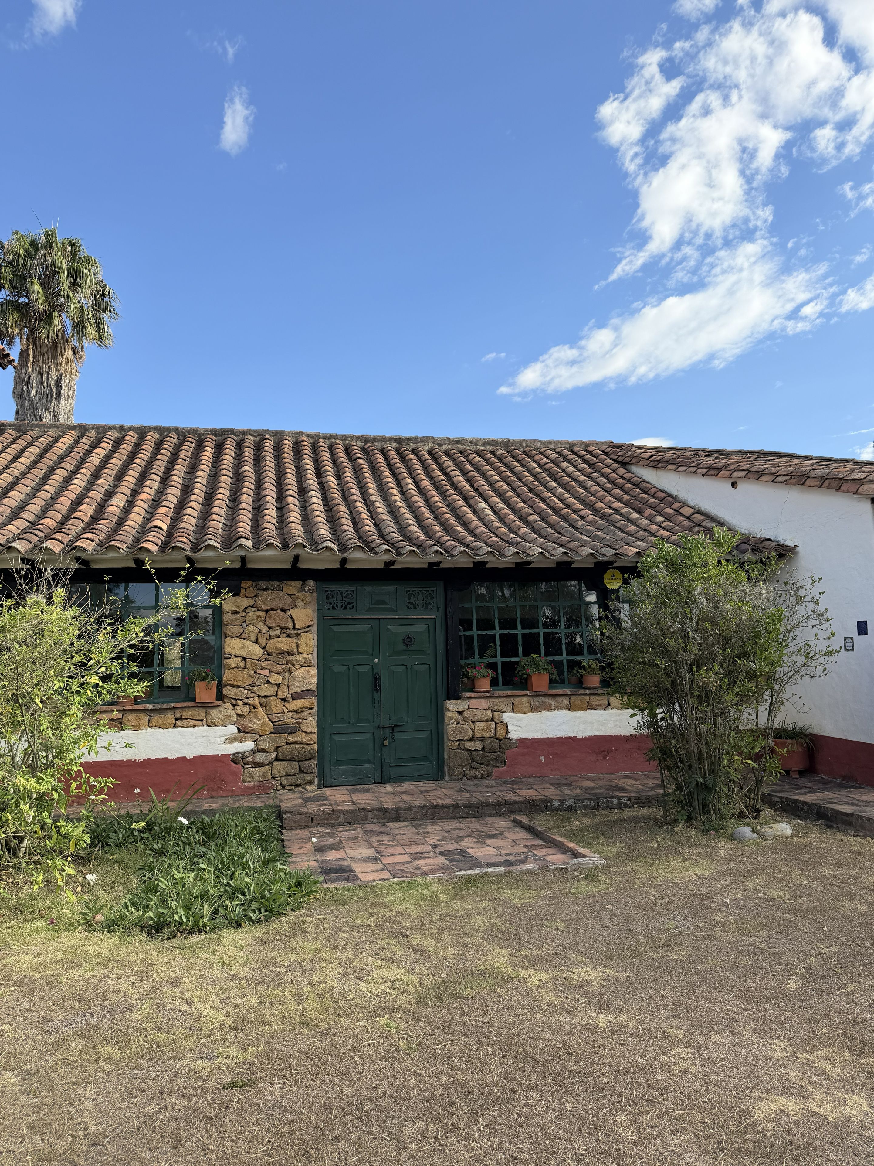 A building with a tiled roof, a green door, and a stone wall.