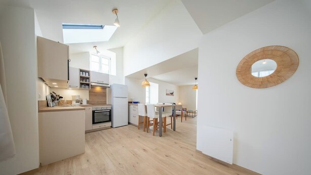 A modern kitchen with a dining area, wooden flooring, and pendant lighting. - Havre de paix - charmante maison avec jardin (Quiberon)