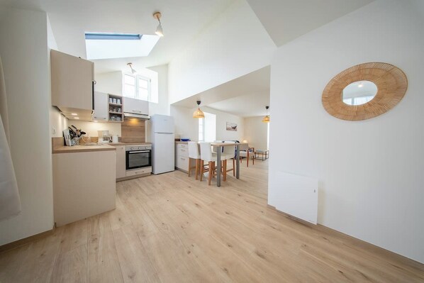 Une cuisine moderne avec un coin repas, un plancher en bois et des luminaires suspendus.