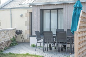 Une terrasse extérieure avec une table et des chaises, un barbecue et une clôture en bois.