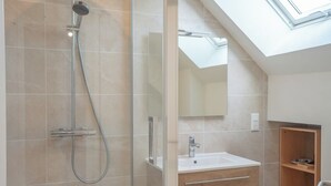 A modern bathroom with a glass-enclosed shower, a white sink, and a wooden vanity. - Havre de paix - charmante maison avec jardin (Quiberon)