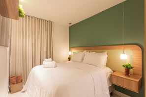 A hotel room with a bed, a nightstand, a lamp, and a potted plant. - Penthouse with jacuzzi, barbecue and sea view. (João Pessoa)