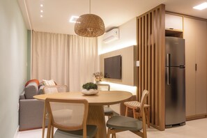 A modern kitchen with a built-in refrigerator, wooden cabinets, and a dining area with a round table and chairs. - Penthouse with jacuzzi, barbecue and sea view. (João Pessoa)