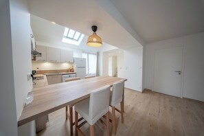 Une cuisine moderne avec un plan de travail en bois, des armoires blanches et une lucarne.