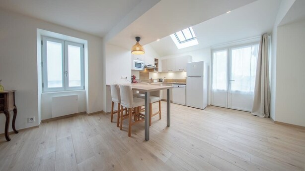 A spacious kitchen with a dining area, large windows, and a skylight. - Petit coin de paradis - charmante maison jardin (Quiberon)