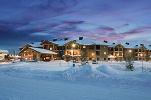 Un chalet comprenant plusieurs bâtiments, des toits recouverts de neige et un ciel dégagé.