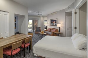 Une chambre d’hôtel comprenant un lit, une table à manger avec des chaises, un canapé, un fauteuil et une lampe.