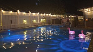 An outdoor swimming pool with a wooden fence, a covered seating area, and a night sky with stars. - My Paradise, a 4-bedroom Home with Hot Tub & Swimming Pool in Soothing Pensacola (Pensacola)