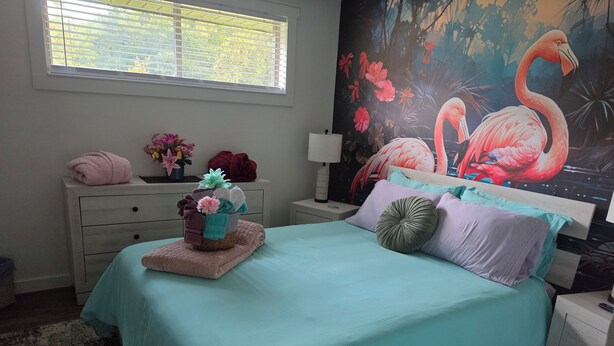 A bedroom with a bed, a nightstand, a dresser, a window, and a wall mural. - My Paradise, a 4-bedroom Home with Hot Tub & Swimming Pool in Soothing Pensacola (Pensacola)