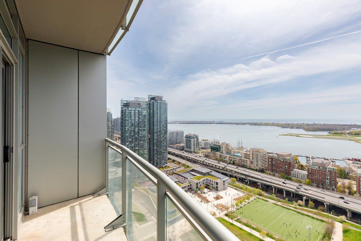 A balcony with a city view, including high-rise buildings and a body of water.