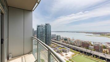 A balcony with a city view, including high-rise buildings and a body of water.