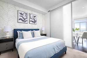 Quarto moderno com uma cama grande, duas mesas de cabeceira e vista para uma varanda.