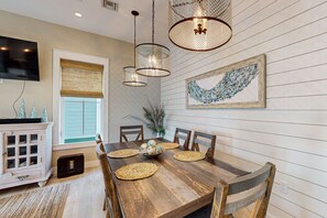 Uma área de refeições com mesa de madeira, jogos americanos trançados e um centro de mesa decorativo.