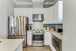 A modern kitchen with stainless steel appliances, white cabinetry, and a tiled backsplash. - Palmilla Beach Resort-137 Palmilla Circle Unit 101 (Port Aransas)