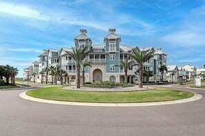 A large, multi-story hotel with a central courtyard, surrounded by palm trees and a well-maintained lawn. - Palmilla Beach Resort-137 Palmilla Circle Unit 101 (Port Aransas)