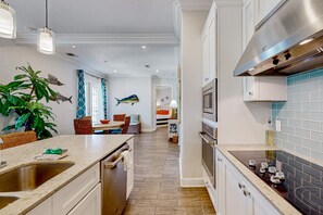 A modern kitchen with a central island, stainless steel appliances, and a herringbone wood floor. - Palmilla Beach Resort-137 Palmilla Circle Unit 103 (Port Aransas)
