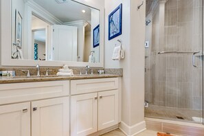 A modern bathroom with a double vanity, a large mirror, and a glass-enclosed shower. - Palmilla Beach Resort-137 Palmilla Circle Unit 103 (Port Aransas)