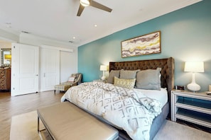 A bedroom with a large bed, a bench, a chair, a nightstand, and a ceiling fan. - Palmilla Beach Resort-137 Palmilla Circle Unit 204 (Port Aransas)