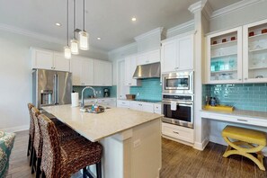 A modern kitchen with white cabinetry, stainless steel appliances, a central island, and a yellow stool. - Palmilla Beach Resort-137 Palmilla Circle Unit 204 (Port Aransas)