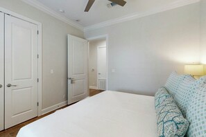 A bedroom with a large bed, a nightstand, a lamp, and a door leading to another room. - Palmilla Beach Resort-137 Palmilla Circle Unit 205 (Port Aransas)
