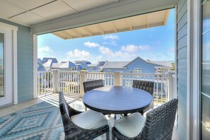 A balcony with a round table and wicker chairs, overlooking a residential area with houses. - Palmilla Beach Resort-137 Palmilla Circle Unit 301 (Port Aransas)