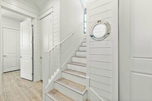 Eine Treppe mit weißer Wandverkleidung und einem Bullaugenfenster.