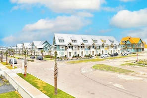 A row of modern, multi-story houses with a central driveway and palm trees. - Palmilla Beach Resort-214 Sunset Avenue Casita 5 (Port Aransas)