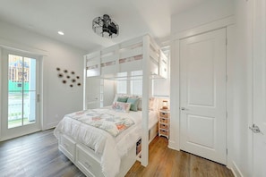 A bedroom with a bunk bed, a ceiling fan, and a view of a construction site through a glass door. - Palmilla Beach Resort-214 Sunset Avenue Casita 5 (Port Aransas)