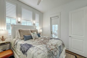 A bedroom with a large bed, a nightstand, a dresser, and a door. - Palmilla Beach Resort-214 Sunset Avenue Casita 7 (Port Aransas)