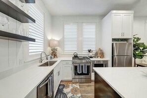 A modern kitchen with white cabinetry, stainless steel appliances, and a central island. - Palmilla Beach Resort-214 Sunset Avenue Casita 7 (Port Aransas)